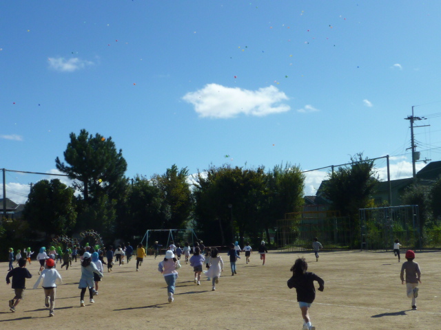 飛んでいく風船をおって駆け出していく子どもたちの写真